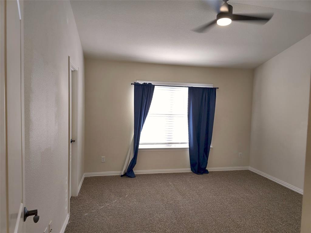 Neutral-toned room featuring high vaulted ceilings, wall-to-wall carpeting, and a ceiling-mounted light fixture with integrated fan