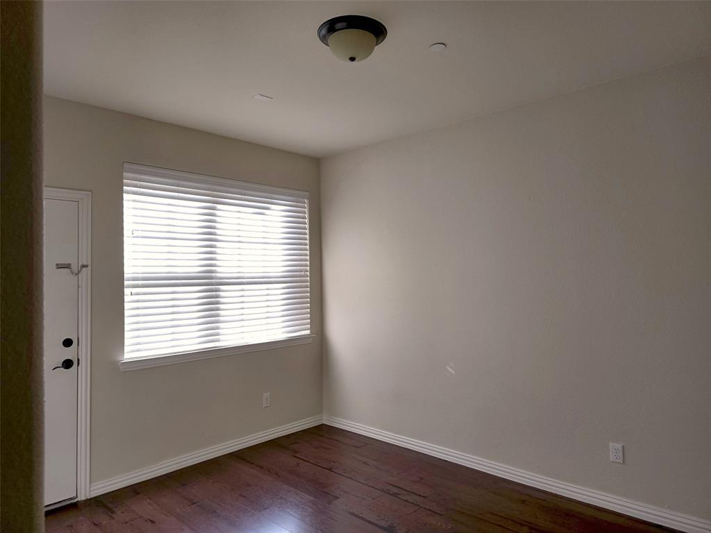 Room featuring wood-finish flooring, a neutral wall palette, large window with horizontal blinds, and flush-mount overhead lighting Room featuring wood-finish flooring, a neutral wall palette, large window with horizontal blinds, and flush-mount overhead lighting