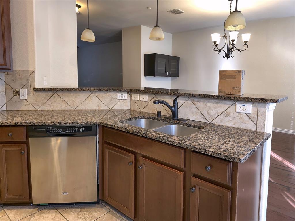 Kitchen featuring stone-finish countertops, diagonal tile backsplash, stainless steel dishwasher, dual-basin under-mount sink with matte black faucet, and wood-finish cabinetry