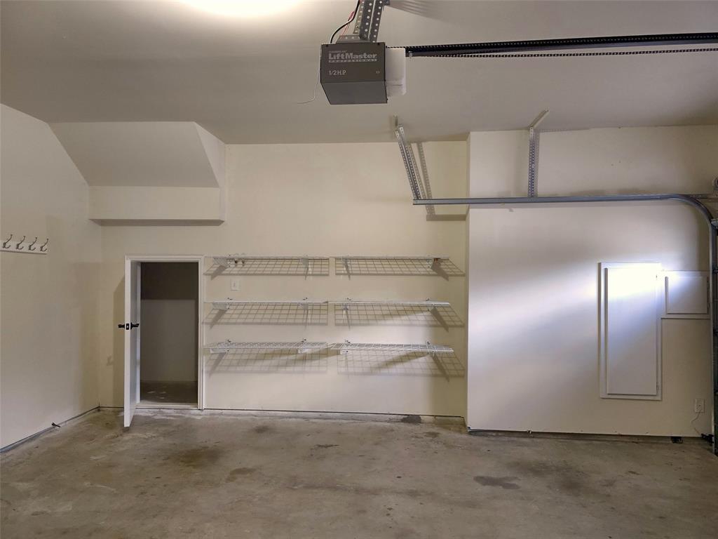 Garage featuring a concrete floor, motorized door opener, wall-mounted wire shelving, and built-in storage panels