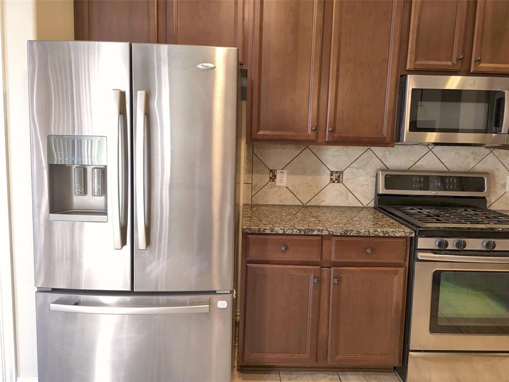 Stainless steel French door refrigerator, built-in microwave, gas range, wood cabinetry, and stone-tiled backsplash