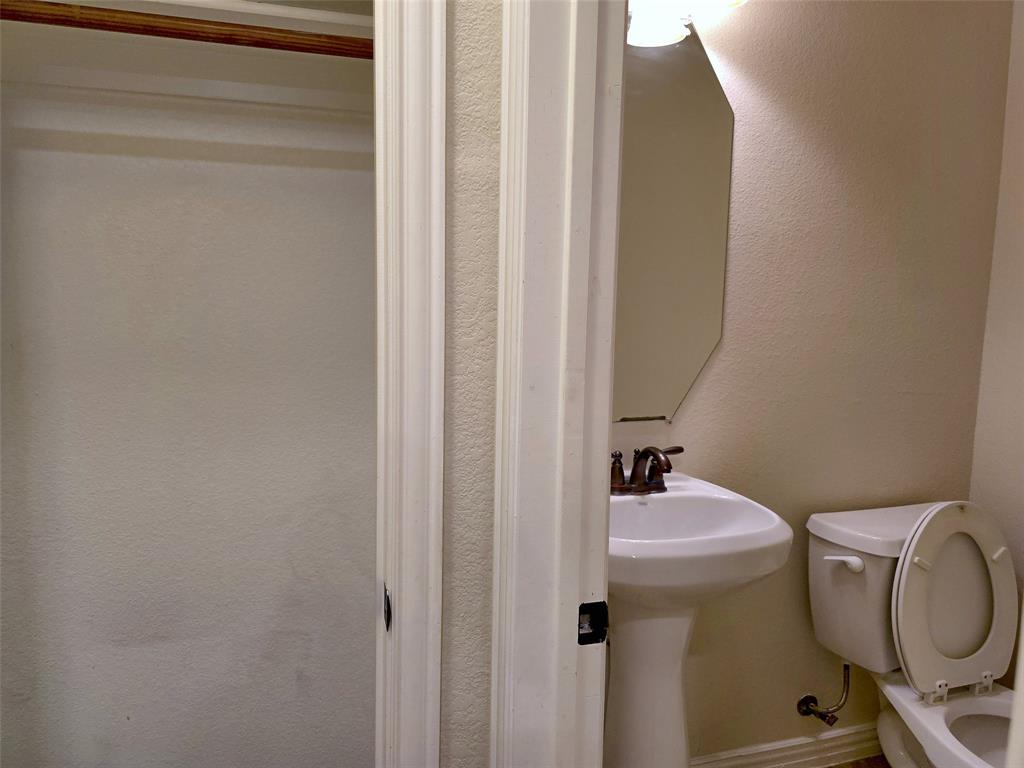 Pedestal sink with a dual-handle metal faucet, wall-mounted geometric mirror, and built-in closet storage