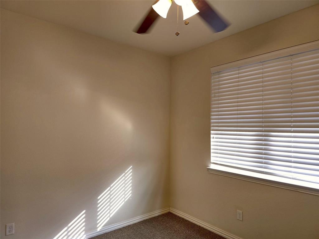Neutral-toned interior walls, neutral-toned carpeting, ceiling-mounted fan with integrated lighting, and horizontal window blinds Neutral-toned interior walls, neutral-toned carpeting, ceiling-mounted fan with integrated lighting, and horizontal window blinds
