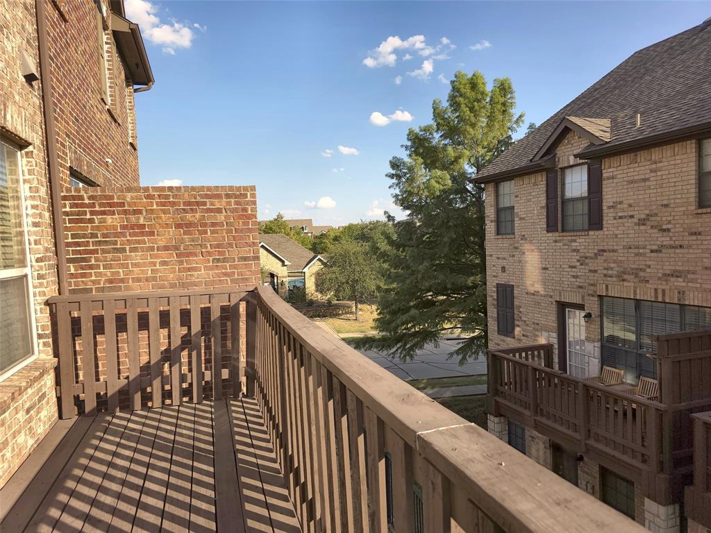 Second-level elevated deck featuring wood-tone railings, composite plank flooring, and a partial brick privacy wall