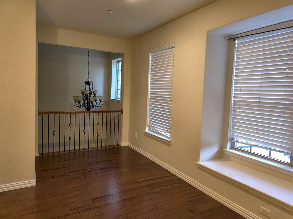 Wood-finish flooring, two deep-sill windows with built-in bench seating, wrought iron balusters, and a tiered decorative chandelier