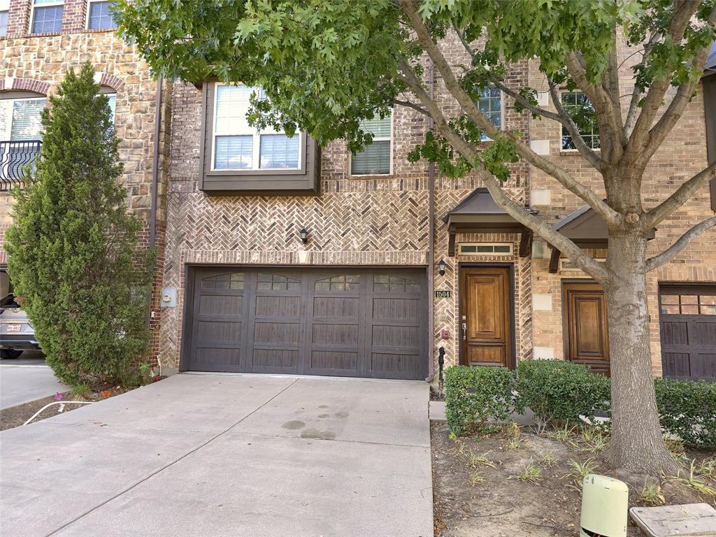 Exterior featuring a herringbone brick facade, wood-finish garage door, arched stonework details, and a dark-stained wood front entry door Exterior featuring a herringbone brick facade, wood-finish garage door, arched stonework details, and a dark-stained wood front entry door