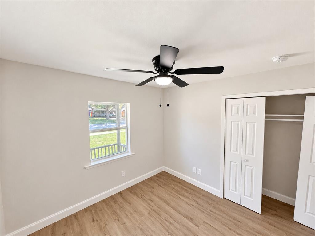 Neutral-toned interior featuring wood-finish flooring, a ceiling fan with integrated lighting, and a closet with bifold doors