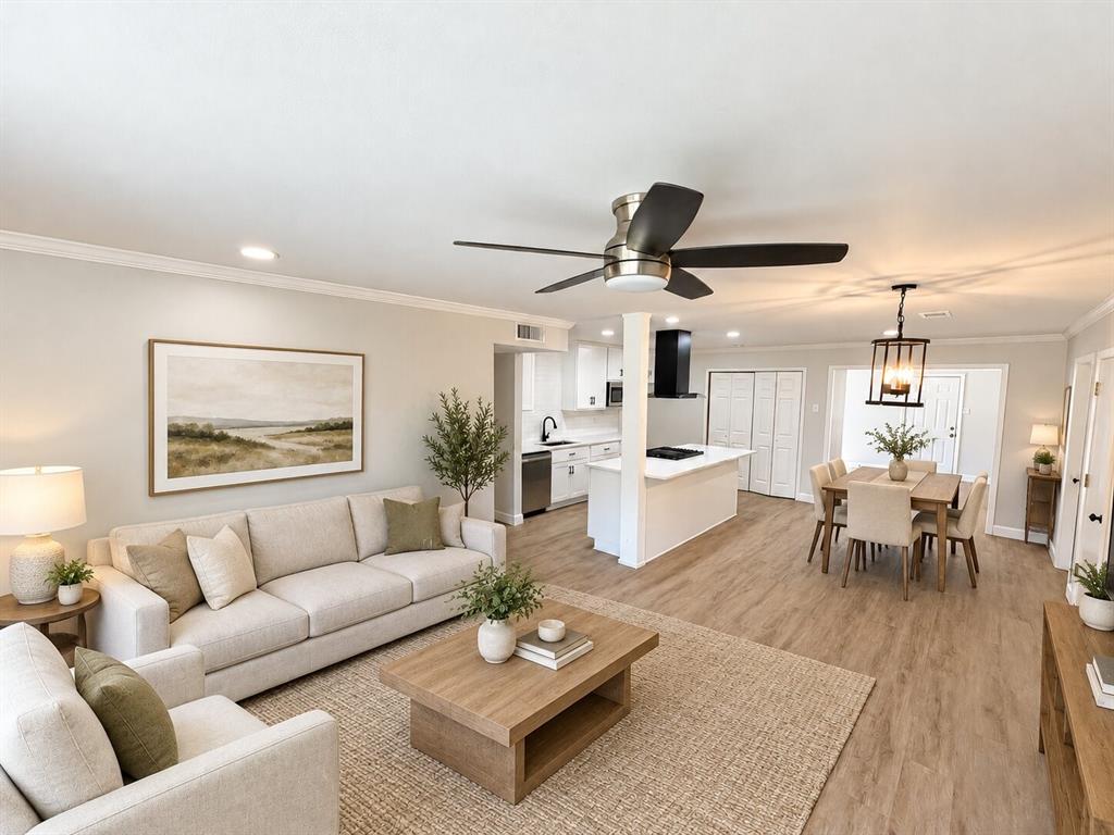 Open-concept interior featuring wood-finish flooring, a kitchen island with stone-finish countertops, matte black plumbing fixtures, a modern ceiling fan, and recessed lighting Open-concept interior featuring wood-finish flooring, a kitchen island with stone-finish countertops, matte black plumbing fixtures, a modern ceiling fan, and recessed lighting