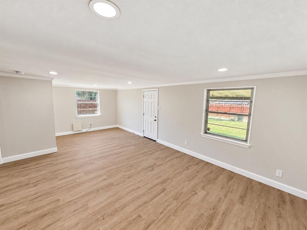 Spacious room featuring wood-finish flooring, recessed lighting, crown molding, and dual windows Spacious room featuring wood-finish flooring, recessed lighting, crown molding, and dual windows