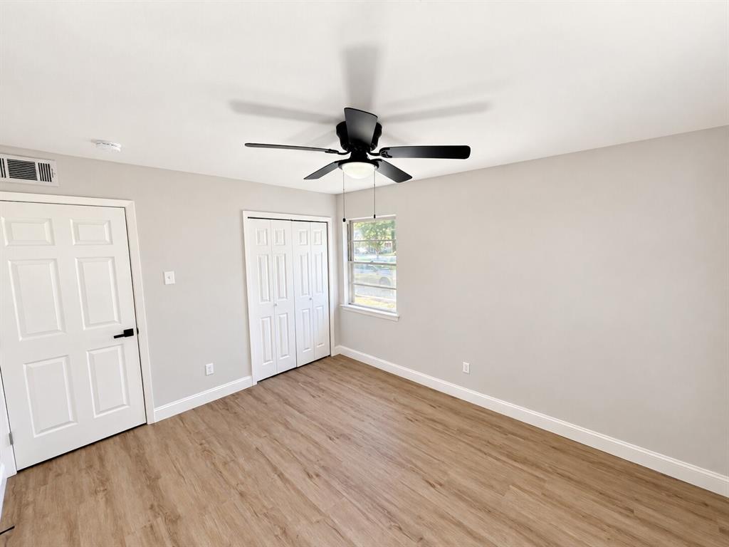 Wood-finish flooring, neutral wall tones, multi-panel doors, and a ceiling fan with integrated lighting