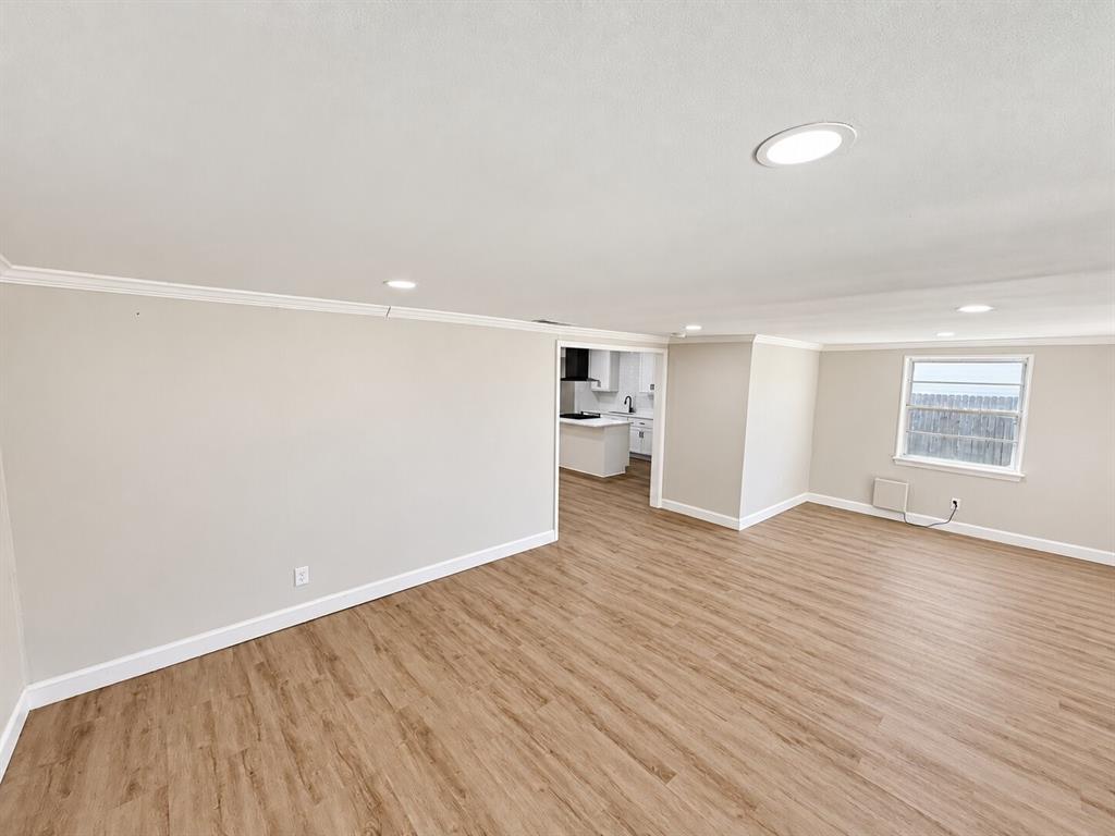 Open interior space featuring wood-finish flooring, recessed lighting, neutral wall paint, and crown molding Open interior space featuring wood-finish flooring, recessed lighting, neutral wall paint, and crown molding