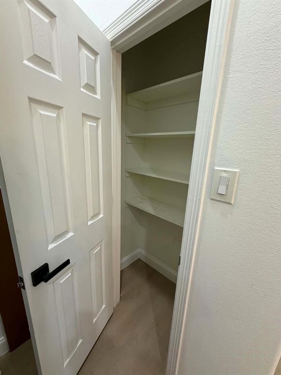 Pantry featuring a six-panel door with matte black hardware and three levels of fixed shelving