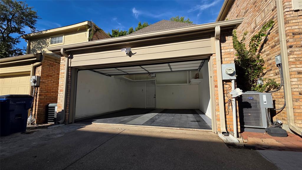 Attached two-car garage featuring segmented flooring, high-contrast wall finishes, and overhead lighting