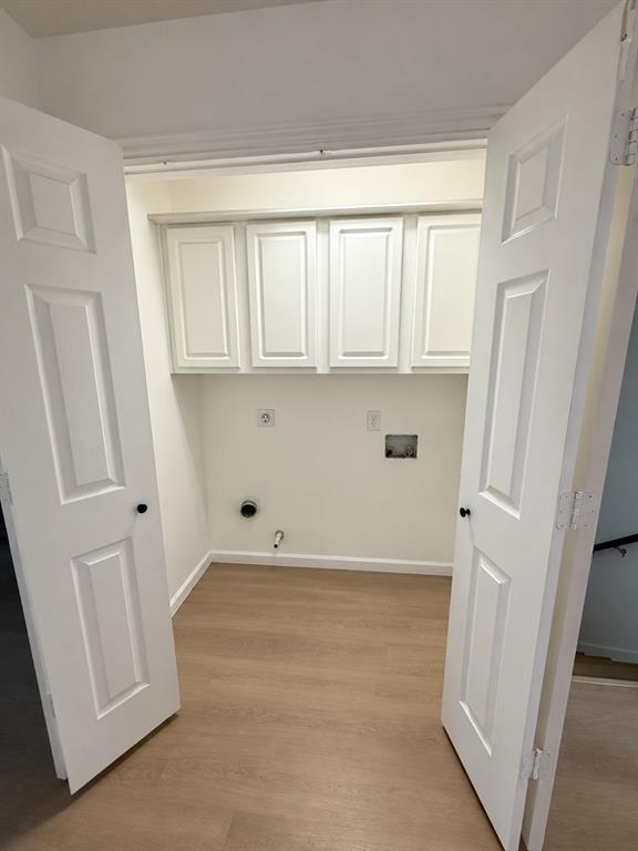Utility closet featuring white raised-panel cabinetry, wood-finish flooring, and double swing doors