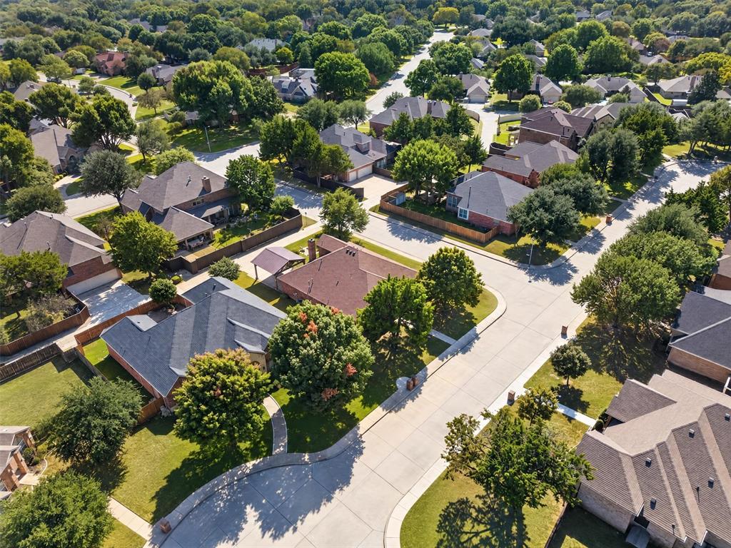 Aerial perspective of a residential neighborhood featuring paved concrete streets, varying lot sizes, established mature tree canopy, and multi-pitched asphalt shingle roofs