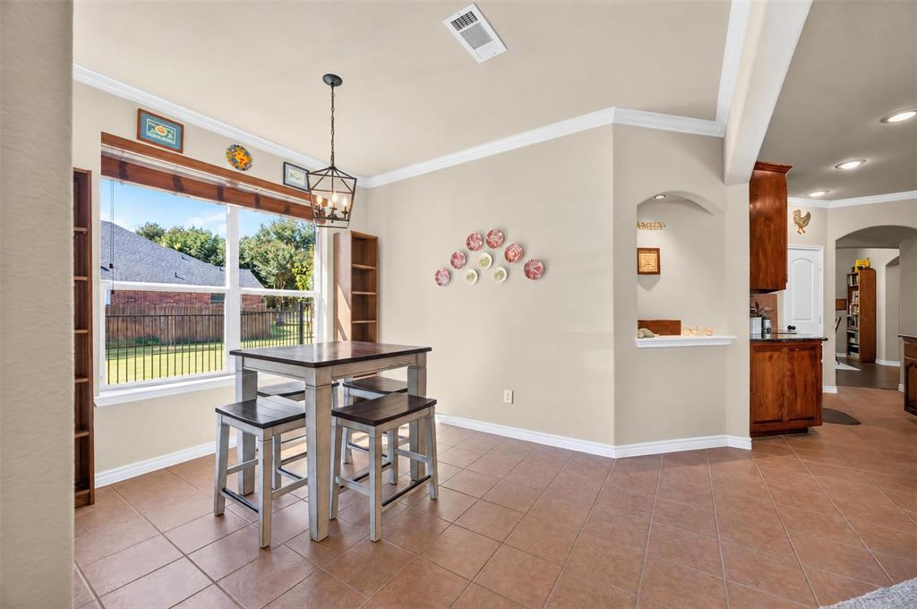Dining area featuring tile flooring, crown molding, an arched wall cutout, and a hanging metal pendant light fixture