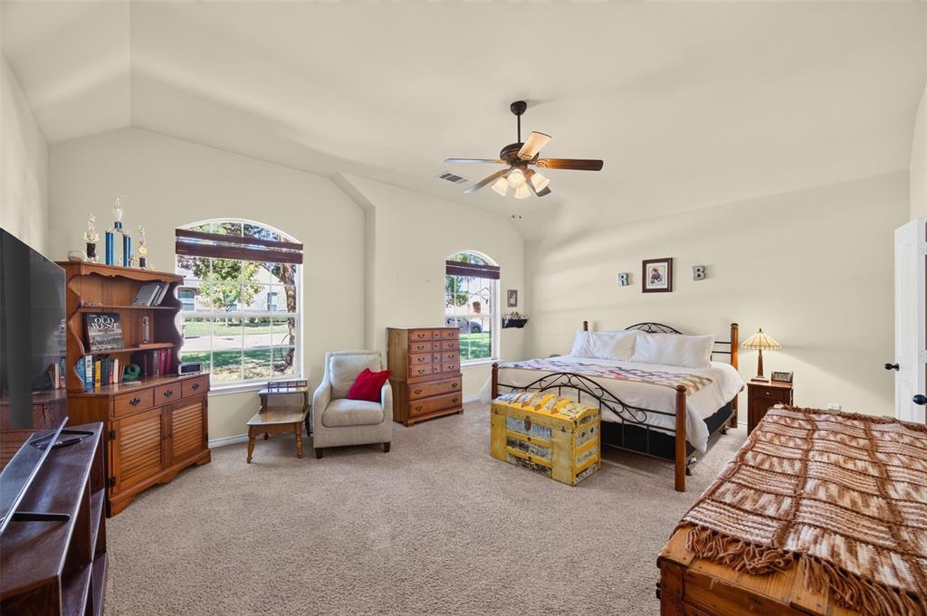 Vaulted ceilings, carpeting, dual arched windows, and a ceiling fan with integrated lighting