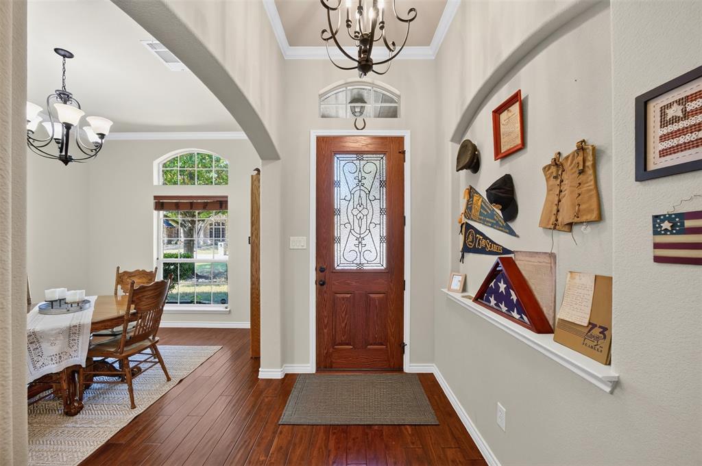 Foyer featuring arched entryway, wood-finish flooring, recessed wall niche, and front door with decorative glass insert and transom window