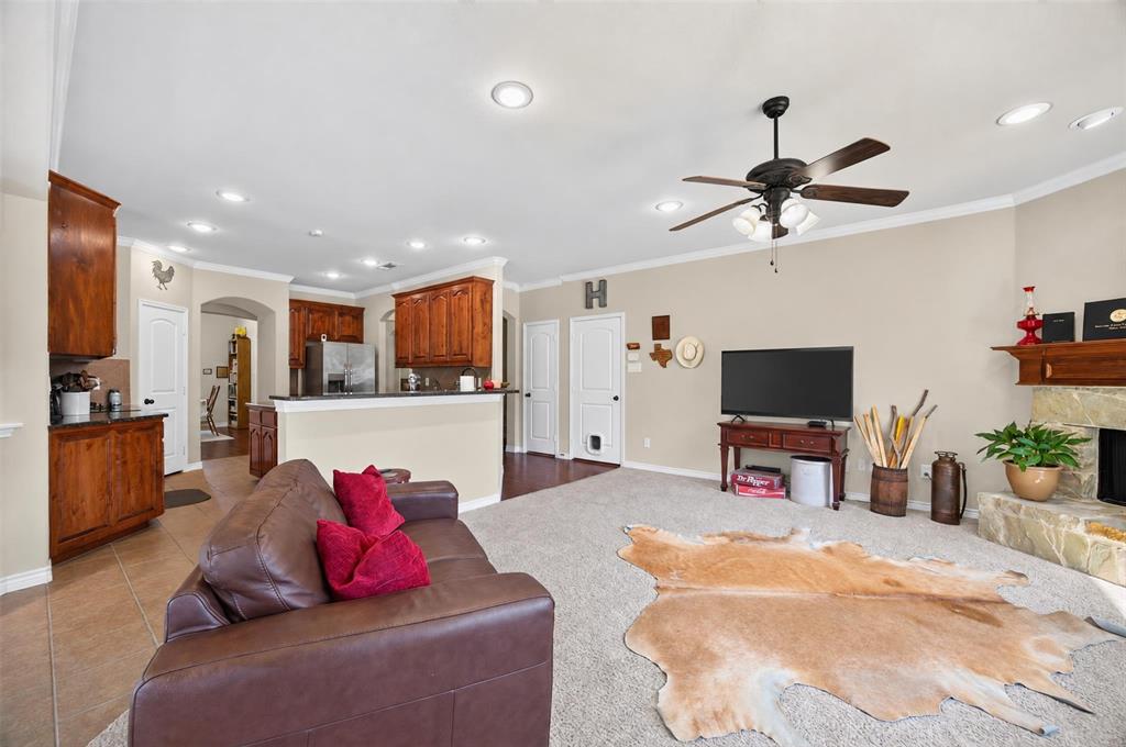 Open-concept living space featuring wood-finish cabinetry, a stone fireplace hearth, recessed lighting, and a ceiling fan