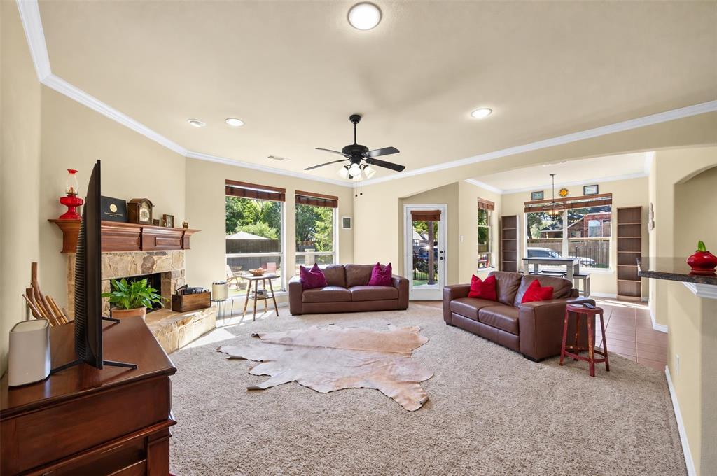 Living area featuring a stone-surround fireplace with a wood mantel, vaulted ceilings, neutral wall-to-wall carpeting, recessed lighting, and large windows