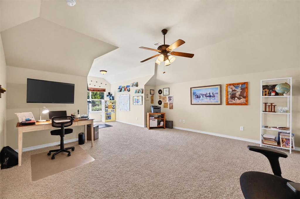 Vaulted ceiling, wall-to-wall carpeting, and a multi-blade ceiling fan with integrated lighting