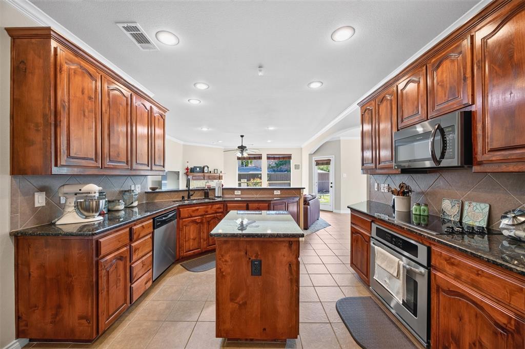 Kitchen featuring stained wood cabinetry, stone-surface countertops, central island, tile backsplash, and recessed lighting