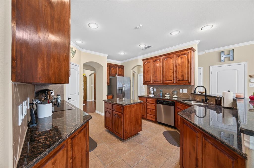 Kitchen featuring wood cabinetry, stone countertops, a center island, stainless steel appliances, and recessed lighting