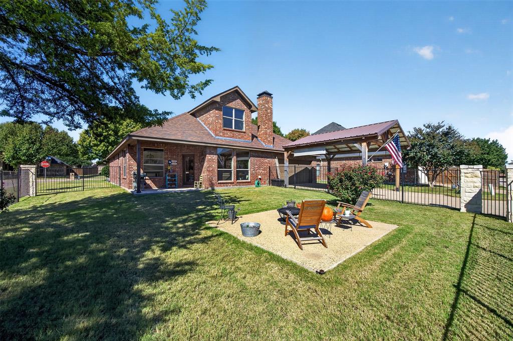 Brick exterior residence featuring a gravel patio area, detached wooden pavilion, and fenced perimeter