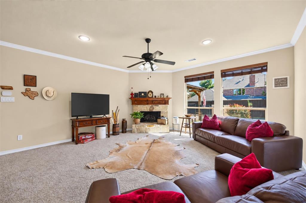 Stone-surround fireplace with a wooden mantel, neutral wall paint, recessed lighting, multi-blade ceiling fan, and large windows