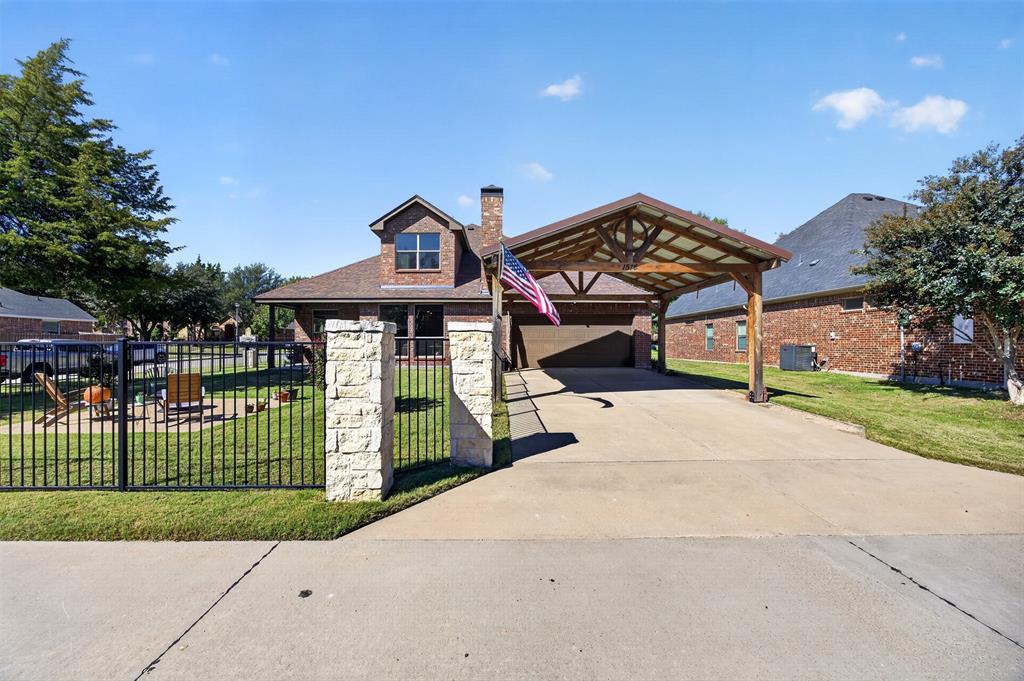 Brick exterior featuring a detached timber-frame carport, stone-capped fencing, and concrete driveway