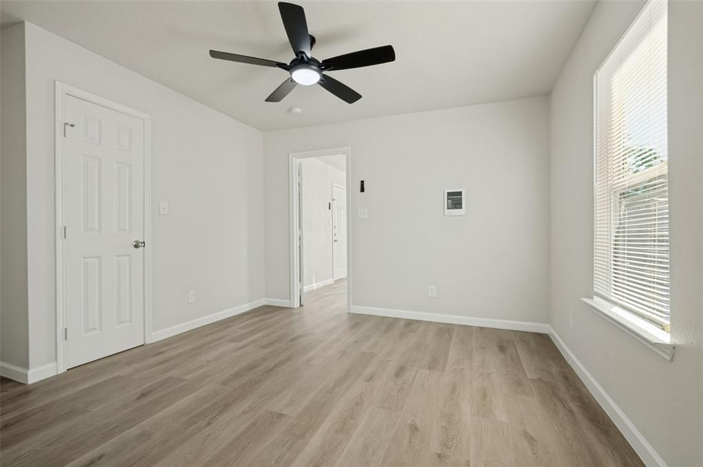 Neutral interior space featuring wood-finish flooring, a ceiling fan with integrated lighting, and a window with horizontal blinds Neutral interior space featuring wood-finish flooring, a ceiling fan with integrated lighting, and a window with horizontal blinds
