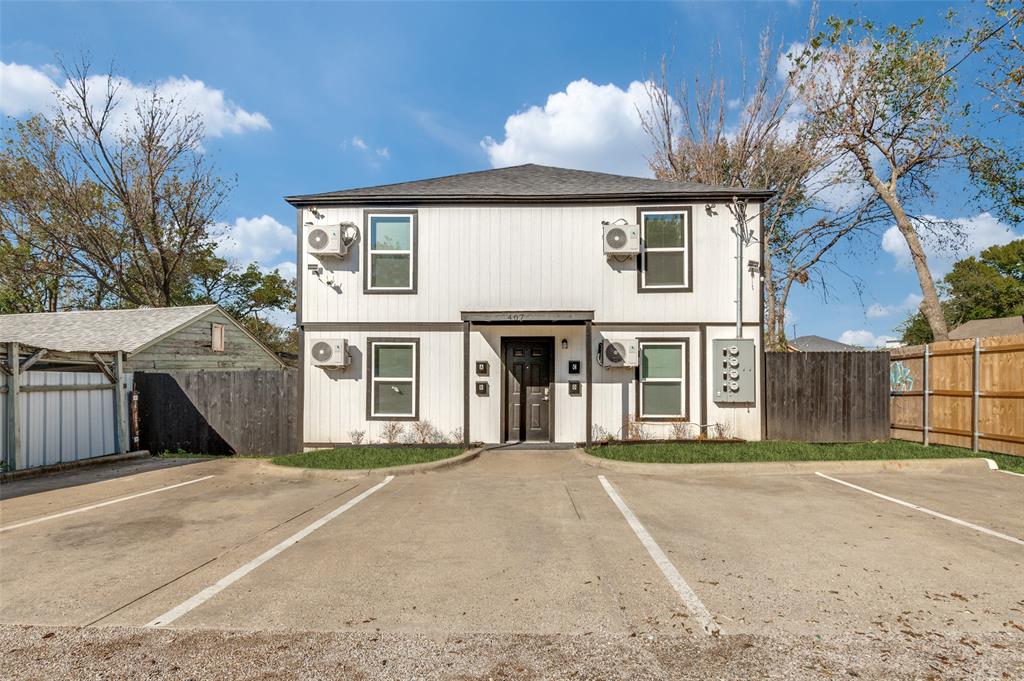 Two-story exterior featuring white vertical siding, dark trim, energy-efficient HVAC units, and an asphalt parking area Two-story exterior featuring white vertical siding, dark trim, energy-efficient HVAC units, and an asphalt parking area