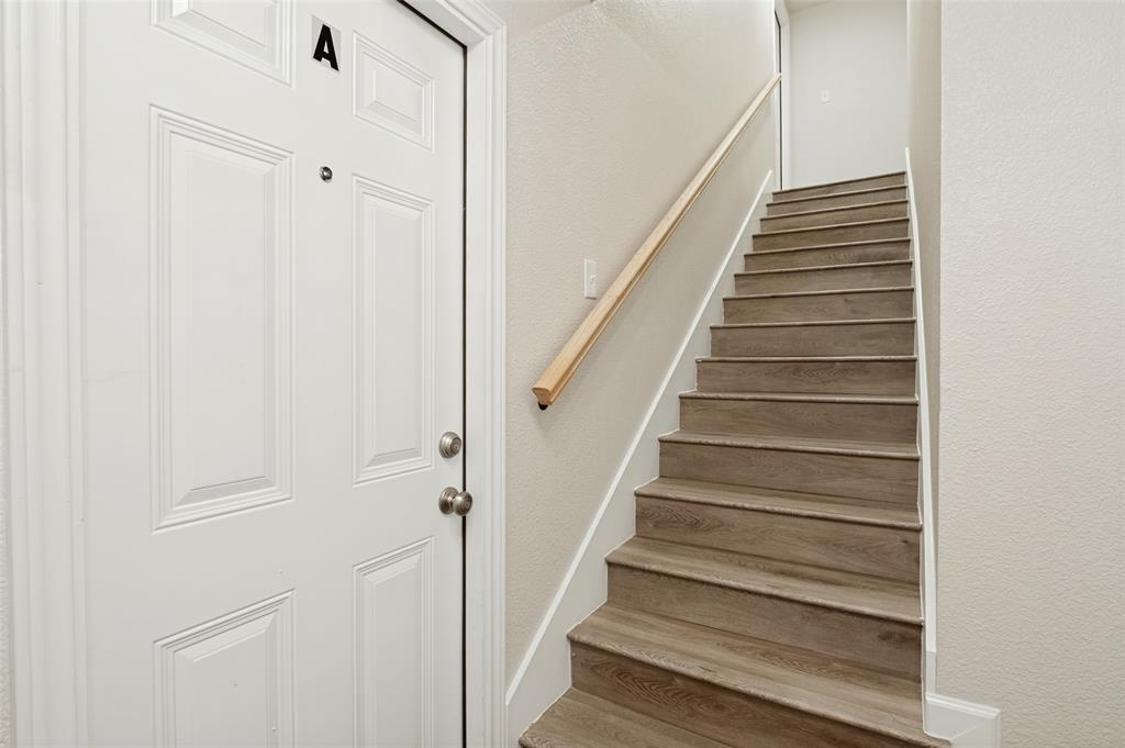 White paneled door with integrated deadbolt and peephole, accompanied by a staircase featuring wood-finish treads and a light-toned wood handrail White paneled door with integrated deadbolt and peephole, accompanied by a staircase featuring wood-finish treads and a light-toned wood handrail