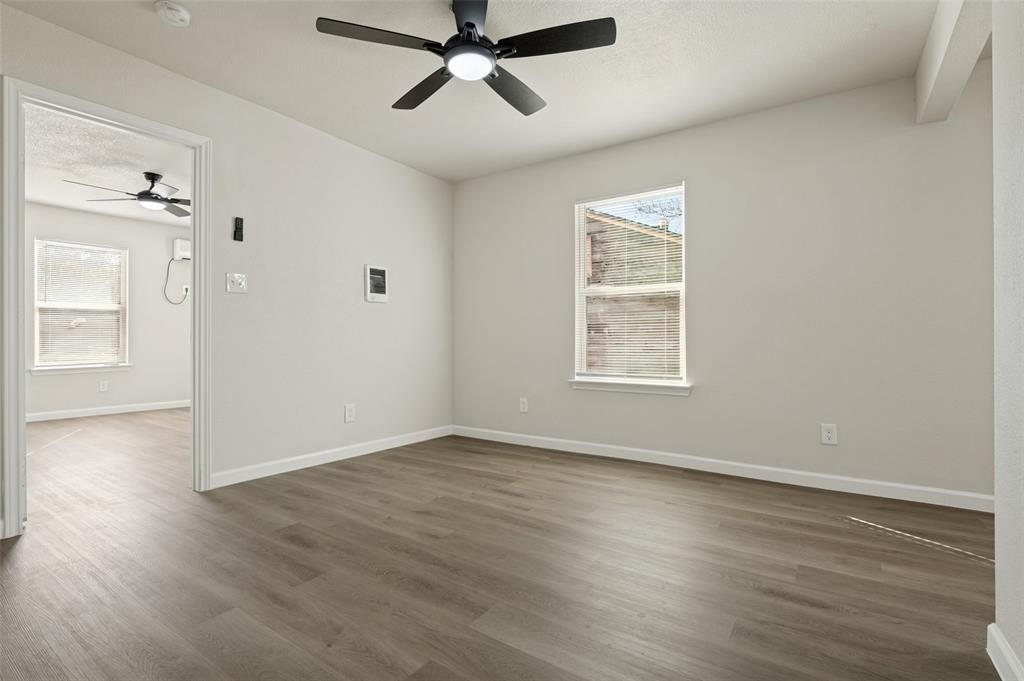 Neutral wall palette featuring wood-finish flooring, recessed windows, and a matte black ceiling fan with integrated lighting Neutral wall palette featuring wood-finish flooring, recessed windows, and a matte black ceiling fan with integrated lighting