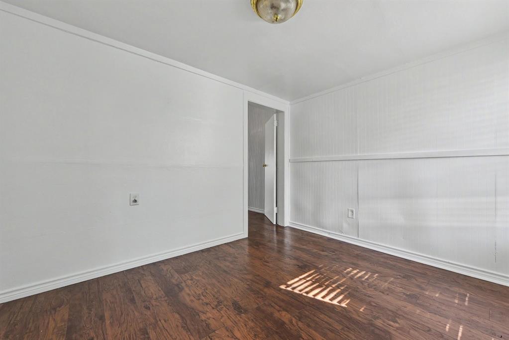 Interior space featuring wood-finish flooring, wainscoting-style wall paneling, and a flush-mount ceiling light fixture