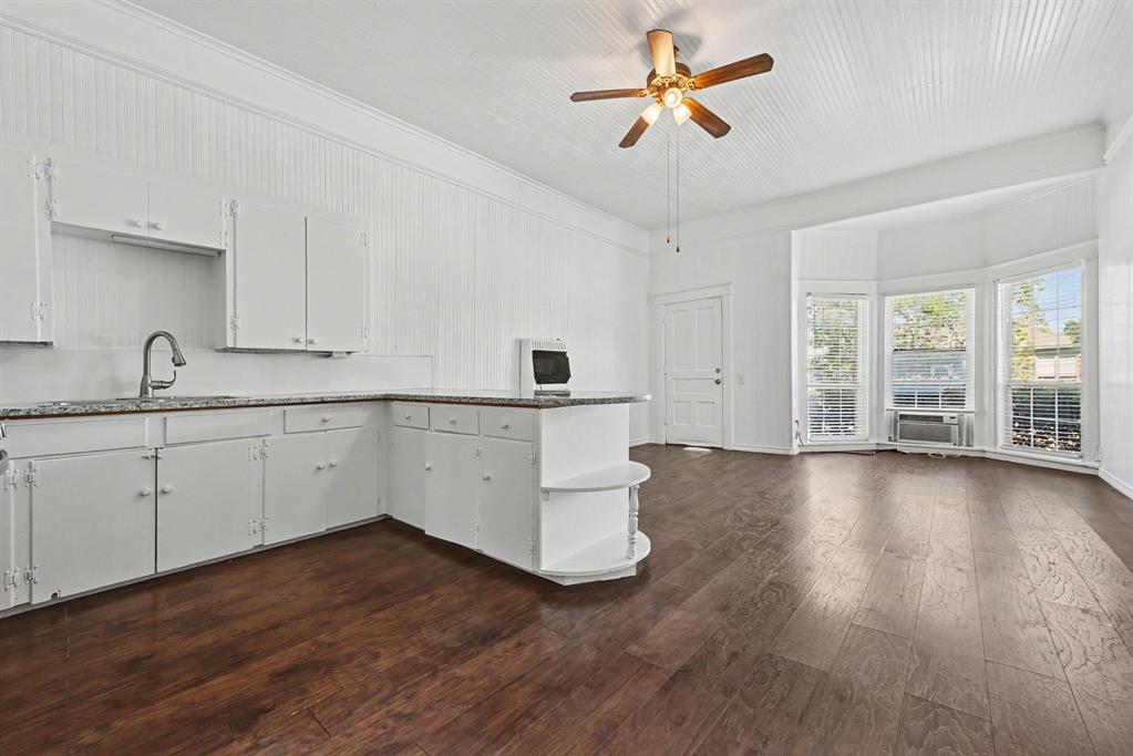 Kitchen featuring stone-finish countertops, wood-finish flooring, beadboard wall paneling, a vaulted ceiling, and a bay window