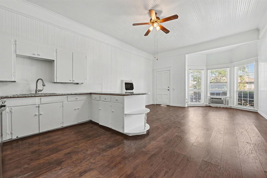 Wood-finish flooring, white paneled wall cladding, vaulted ceiling, and bay windows