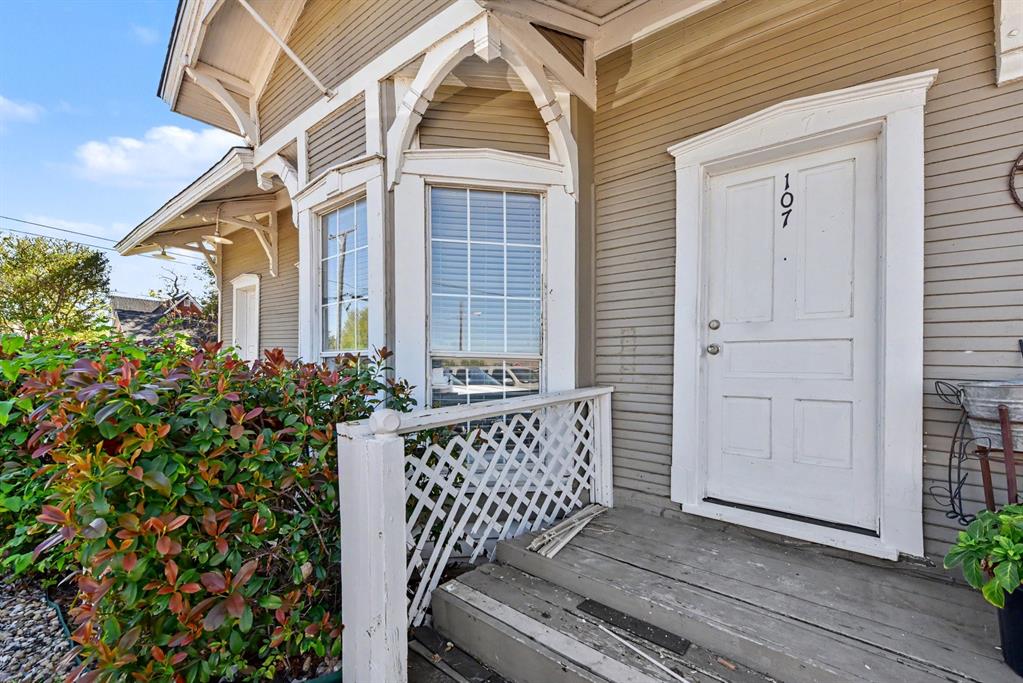 Exterior elevation featuring horizontal lap siding, a bay window with decorative arched woodwork, and a front entrance with a paneled door