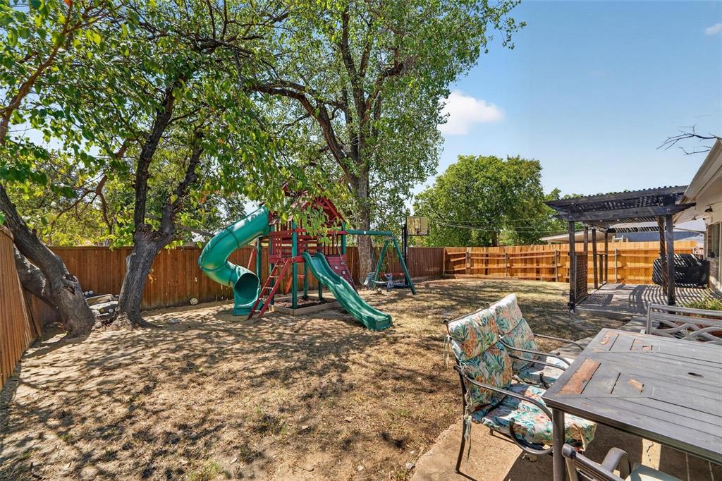 Backyard featuring a wood privacy fence, mature trees, and a wooden pergola