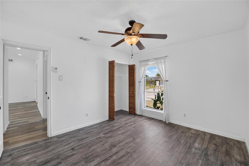 Room featuring wood-finish flooring, a ceiling fan with integrated lighting, and a closet with louvered doors