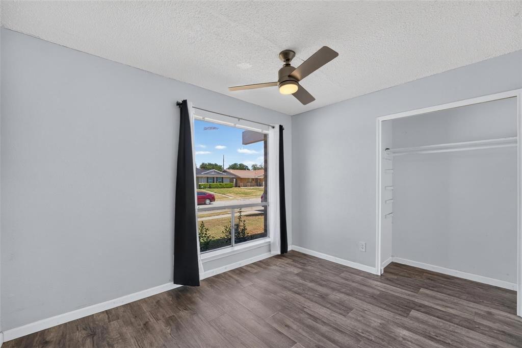 Room featuring wood-finish flooring, a large picture window, and a ceiling fan with integrated lighting