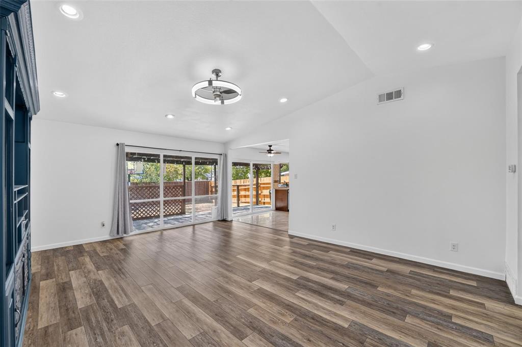 Interior space featuring vaulted ceilings, wood-finish flooring, recessed lighting, a modern circular ceiling fan, and large sliding glass doors Interior space featuring vaulted ceilings, wood-finish flooring, recessed lighting, a modern circular ceiling fan, and large sliding glass doors
