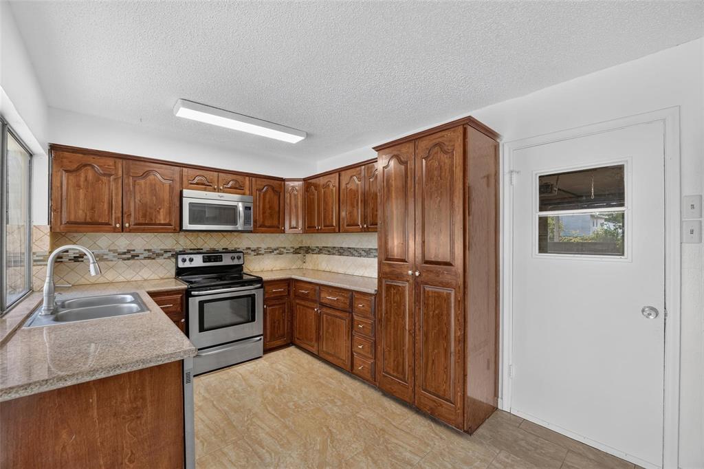 Kitchen featuring wood cabinetry, stone-finish countertops, stainless steel appliances, tiled backsplash, and recessed overhead lighting