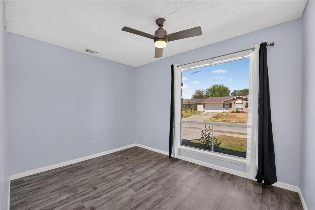 Room featuring wood-finish flooring, a large picture window, and a central ceiling fan with integrated lighting