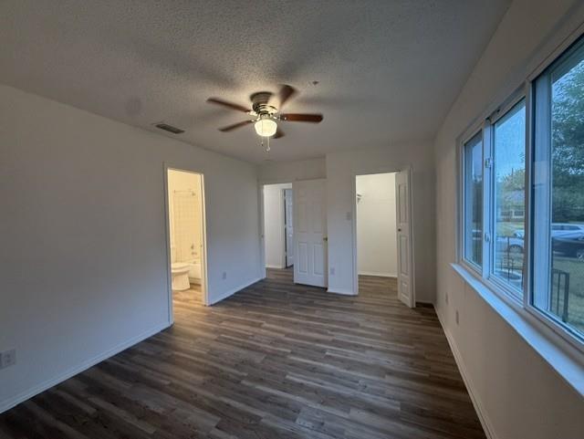 Wood-finish flooring, ceiling fan with integrated lighting, oversized picture windows, and neutral interior wall paint