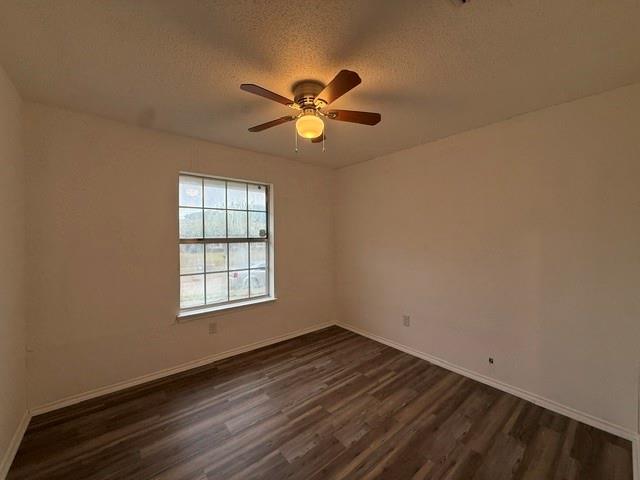 Room featuring wood-finish flooring, a multi-pane window, and a ceiling-mounted light fixture with an integrated fan