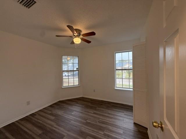Room featuring wood-finish flooring, dual windows, ceiling fan with integrated lighting, and louvered closet doors Room featuring wood-finish flooring, dual windows, ceiling fan with integrated lighting, and louvered closet doors