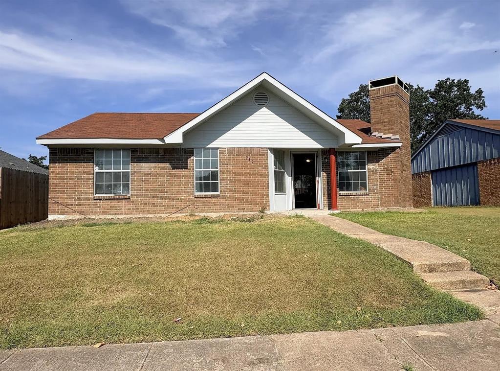 Single-story residence featuring a brick and horizontal siding exterior, prominent masonry chimney, and a concrete walkway Single-story residence featuring a brick and horizontal siding exterior, prominent masonry chimney, and a concrete walkway