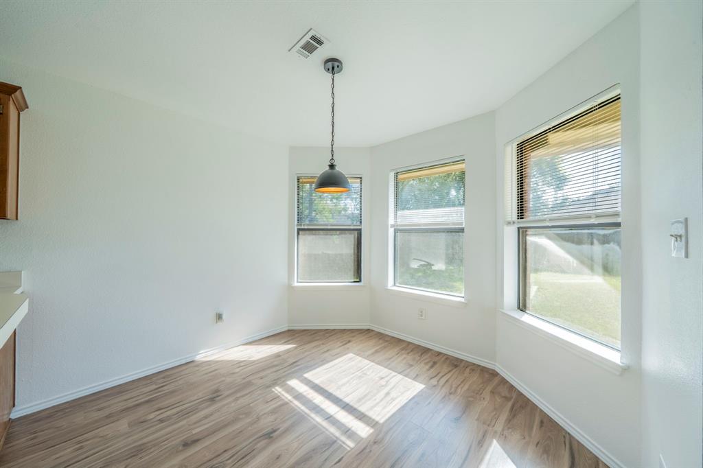Bay window featuring three paneled windows, wood-finish flooring, and a single industrial-style pendant light fixture