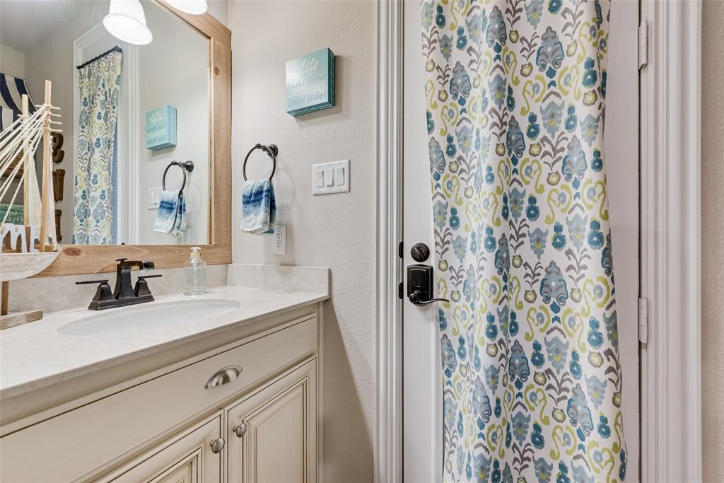 Vanity featuring light-toned cabinetry, a stone-finish countertop with an integrated oval basin, a dark-finish faucet, and a custom wood-framed mirror